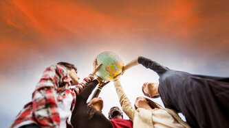Image of people holding up a globe 